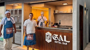 Bar de hotel con diseño moderno, que presenta una barra con un logotipo y un revestimiento de pared de madera.