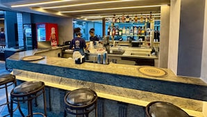 Una zona de bar con mostrador de mármol, taburetes y un refrigerador de Coca-Cola.