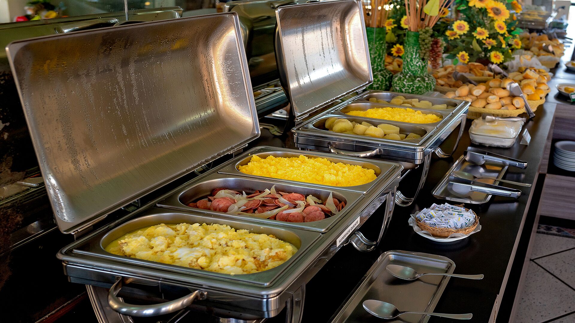 Un buffet proposant divers plats, comme des œufs brouillés, des saucisses et des pommes de terre.