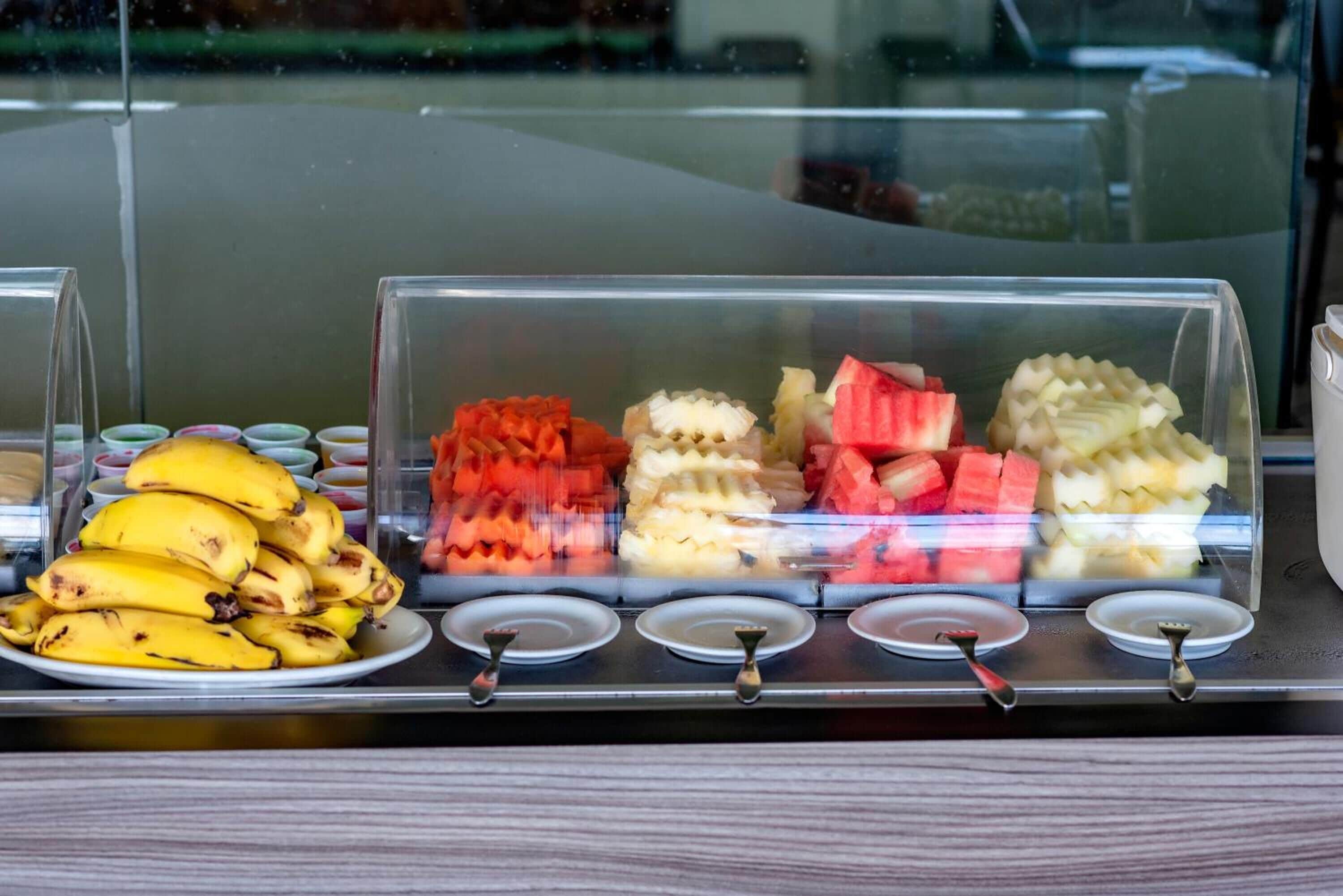 Una vitrina con diversas frutas y un plato de plátanos.