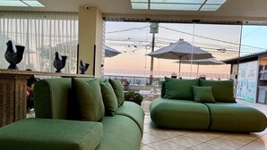 Una habitación amplia con un sofá verde, un sillón verde más pequeño y un ventanal con vistas al cielo.
