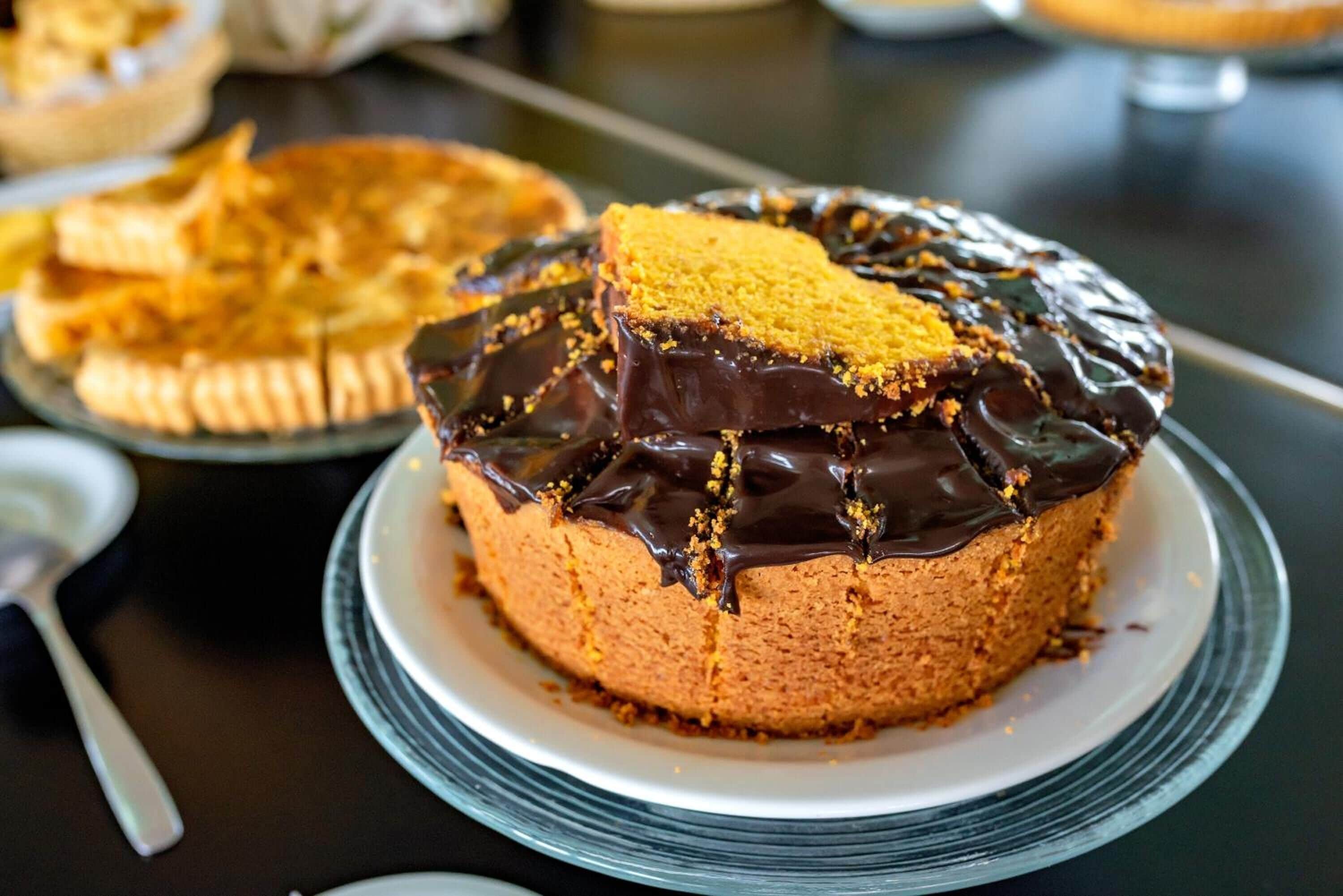 A cake with chocolate glaze and crumbled topping on a glass plate.