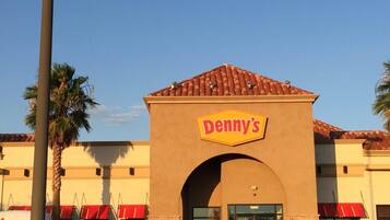 A Denny's restaurant with a red awning and a brown facade.