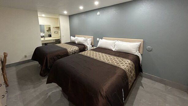 A hotel room with two beds, a mirror, and a small bathroom area. - California Inn & Suites Adelanto US 395 (Adelanto)