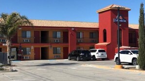 A multi-story hotel with a red facade and a prominent California Inn sign. - California Inn & Suites Adelanto US 395 (Adelanto)