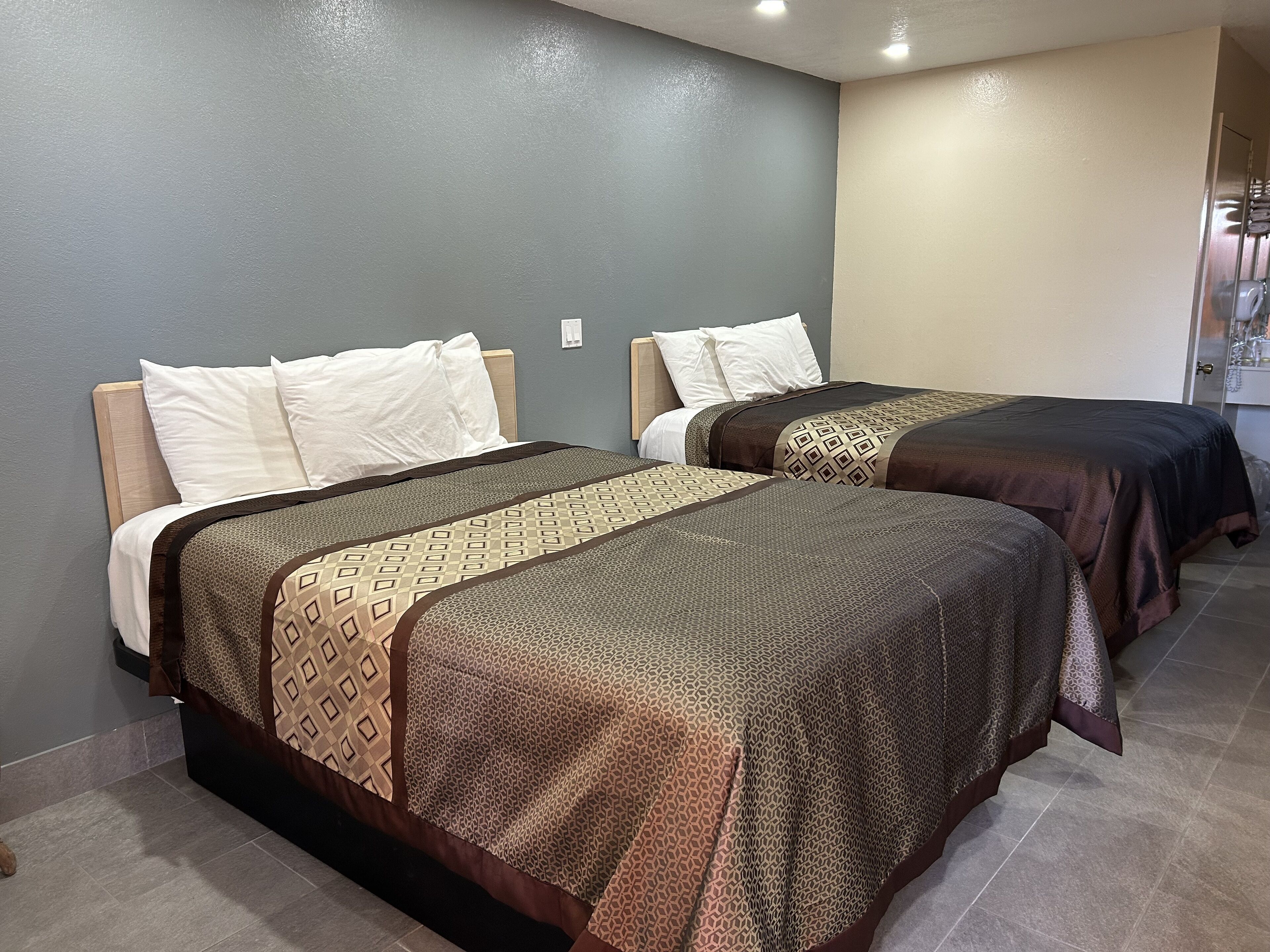 Habitación de hotel con dos camas, cada una con cubrecamas estampados y almohadas blancas.