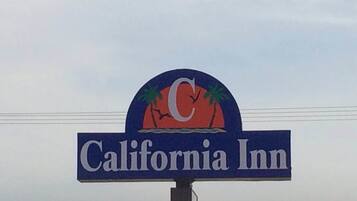 A sign for California Inn with a logo featuring palm trees and a sunset.