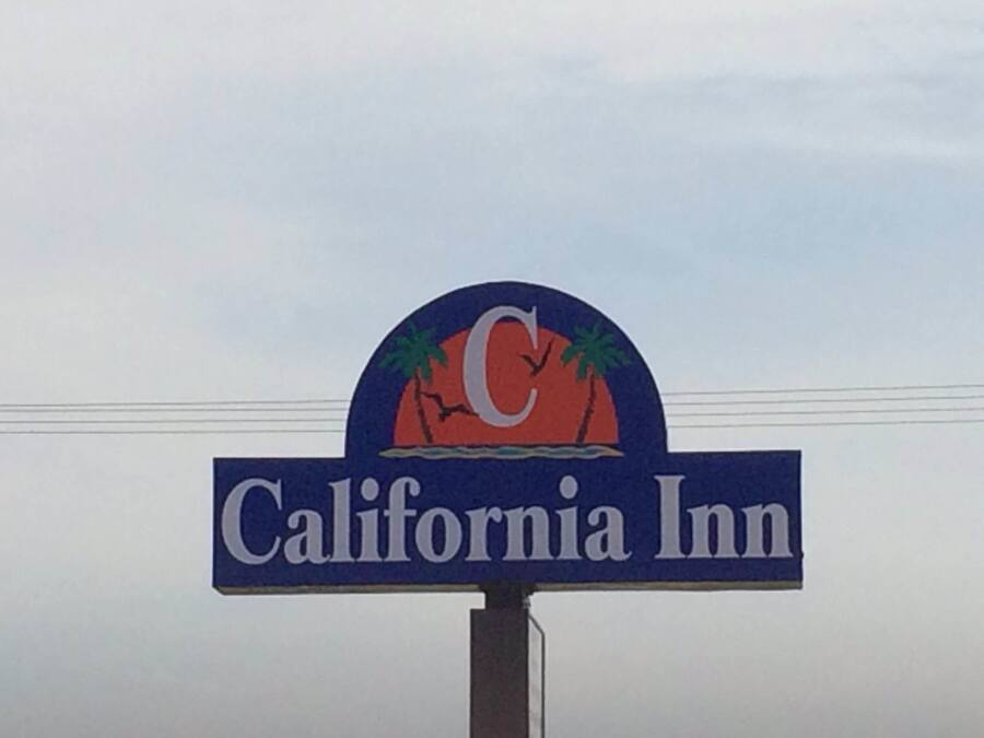 A sign for California Inn with a logo featuring palm trees and a sunset.