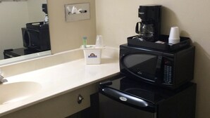 A compact hotel bathroom with a sink, a microwave, a coffee maker, and a small trash bin. - California Inn & Suites Adelanto US 395 (Adelanto)