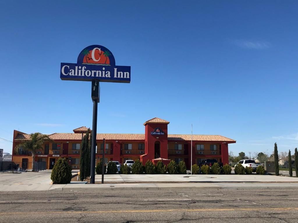 Hotel California Inn con fachada roja, un letrero llamativo y un estacionamiento al frente.