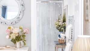 A bedroom with a bed, a dresser, a mirror, and a bathroom visible through an open door. - Ironbridge View Townhouse (Telford)