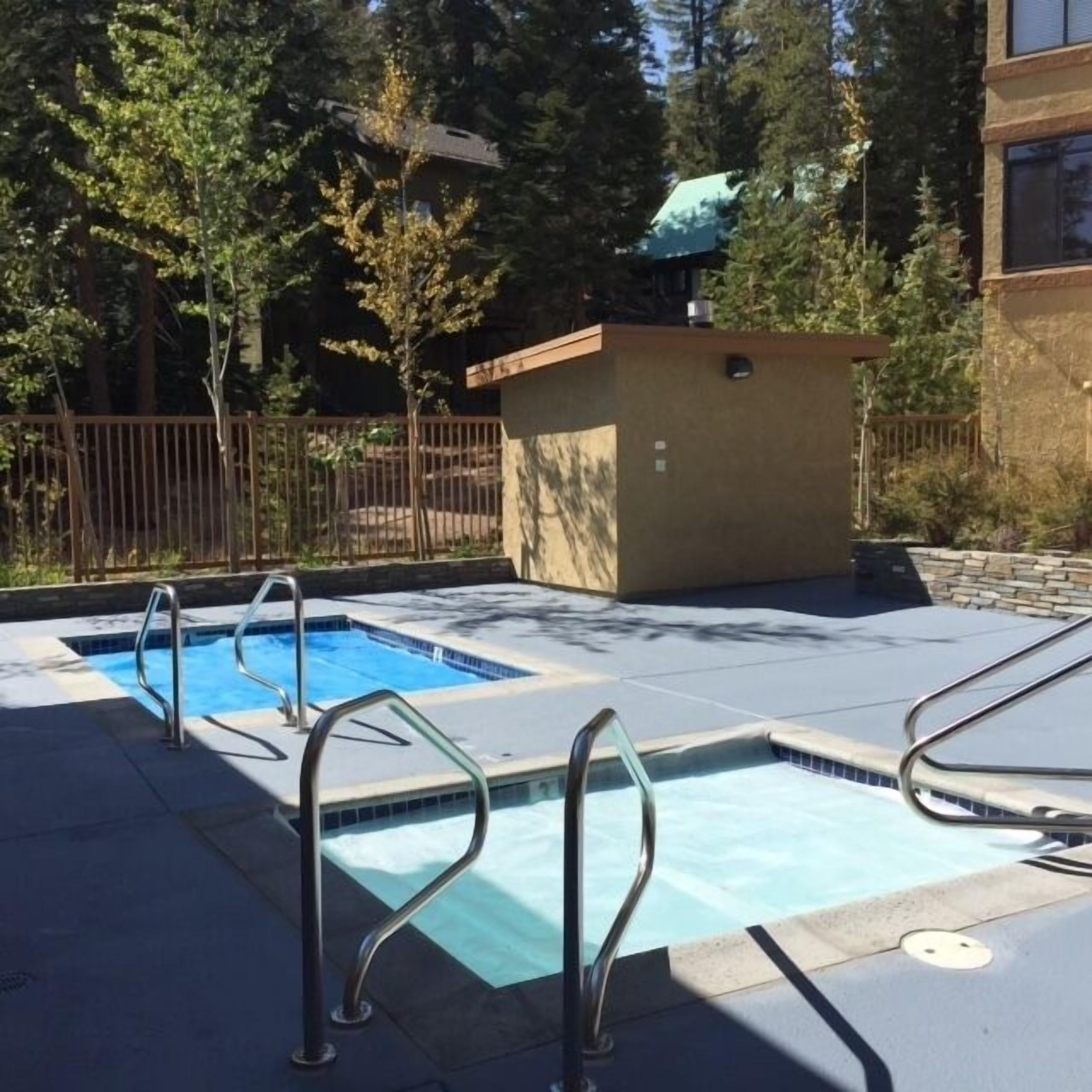 A swimming pool with metal railings and a small building in the background.