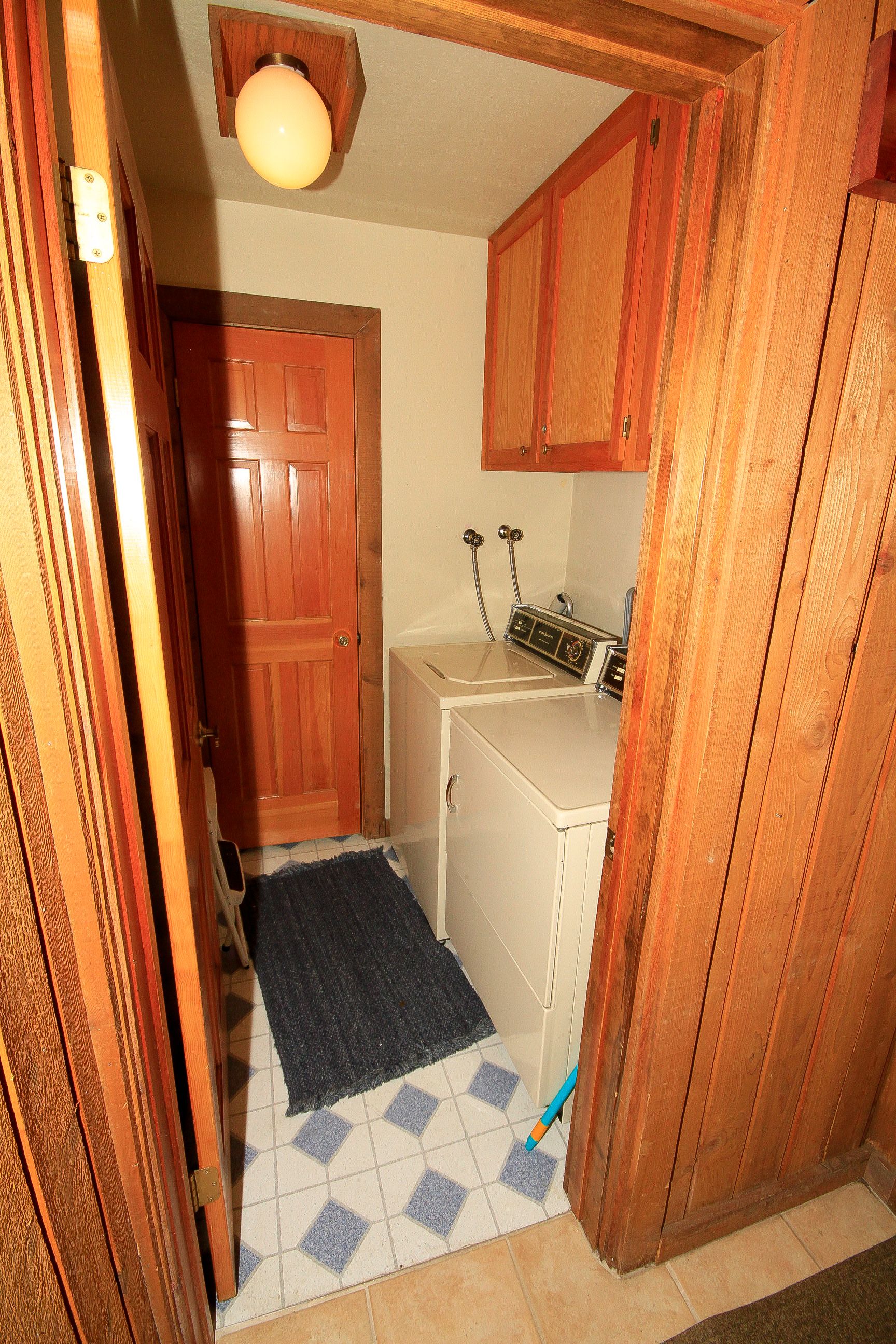 A small laundry room with wooden cabinets, a washing machine, and a dryer.