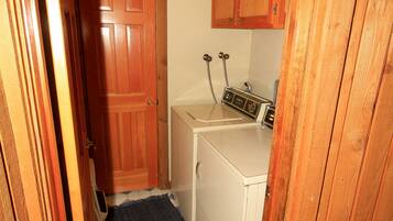 A small laundry room with wooden cabinets, a washing machine, and a dryer.