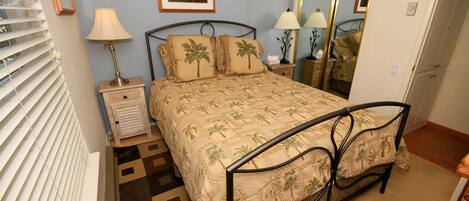 Un dormitorio con cama, mesitas de noche, lámparas, un espejo y una alfombra estampada.
