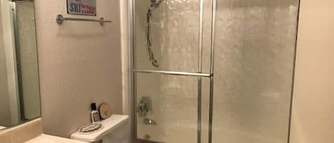 A bathroom with a shower, toilet, and sink.