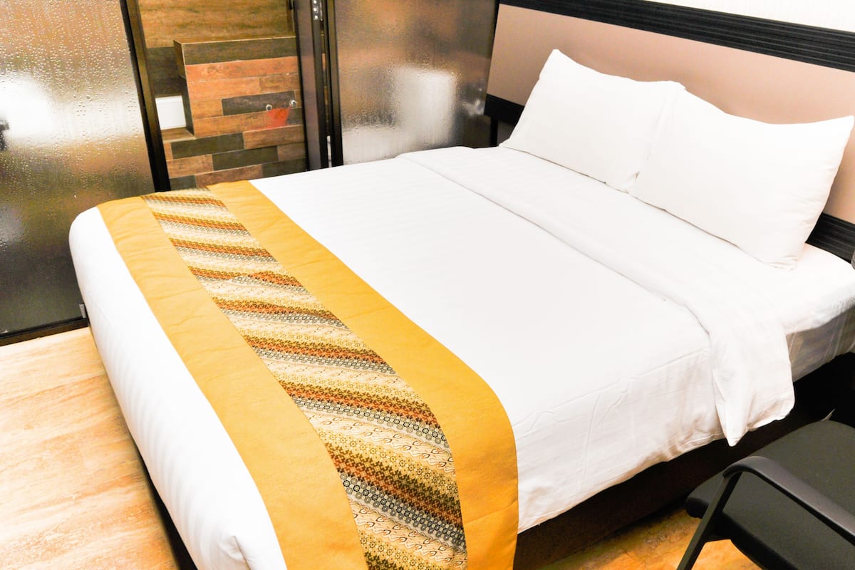 A hotel room with a bed, a nightstand with a phone, and a chair.