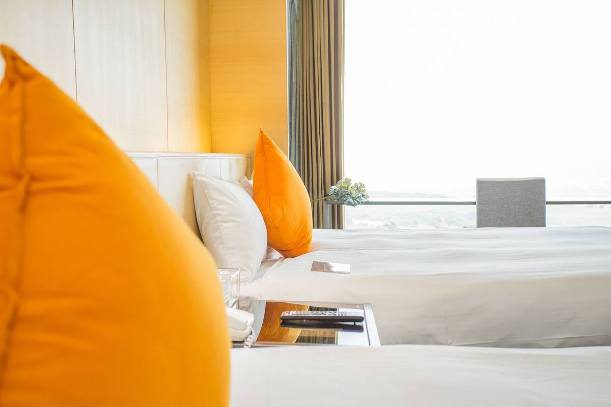 A hotel room with two beds, a view of the sea, and a chair.