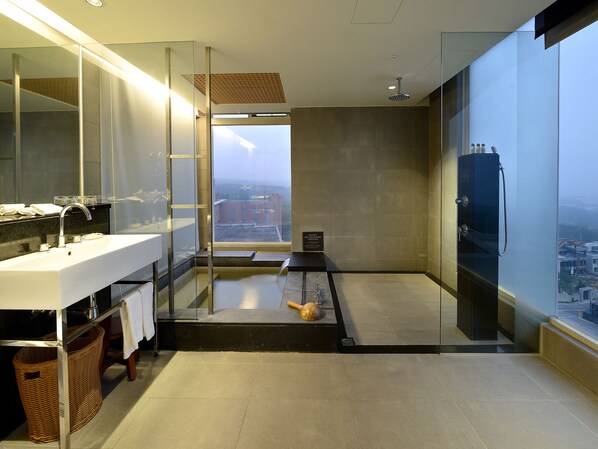 Een moderne badkamer met een grote spiegel, twee wasbakken, een douche en uitzicht op een stadsgezicht door een groot raam.