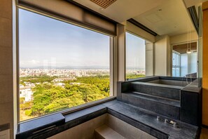 A modern interior with a large window offering a city view, a built-in bench, and a staircase. - Freshfields Hotel (Taichung)