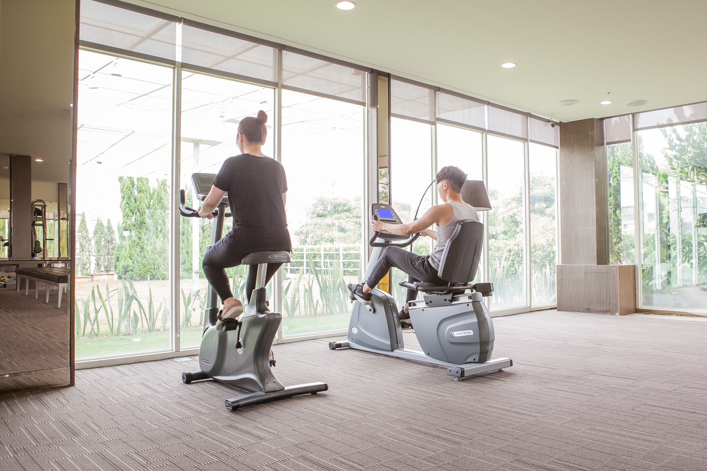 A gym with two stationary bikes and a large window.