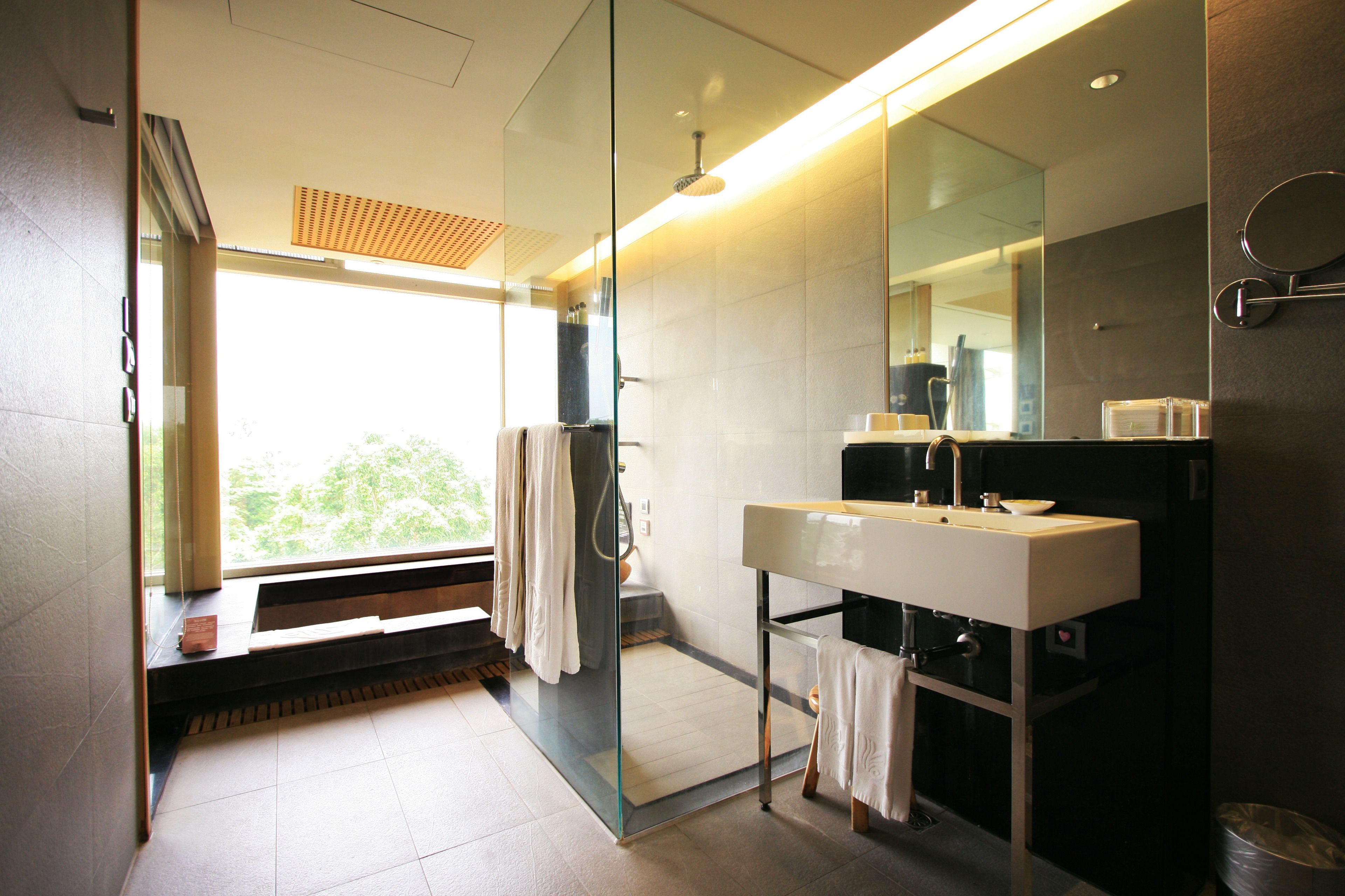 A modern bathroom with a glass shower enclosure, a large mirror, and a white sink.