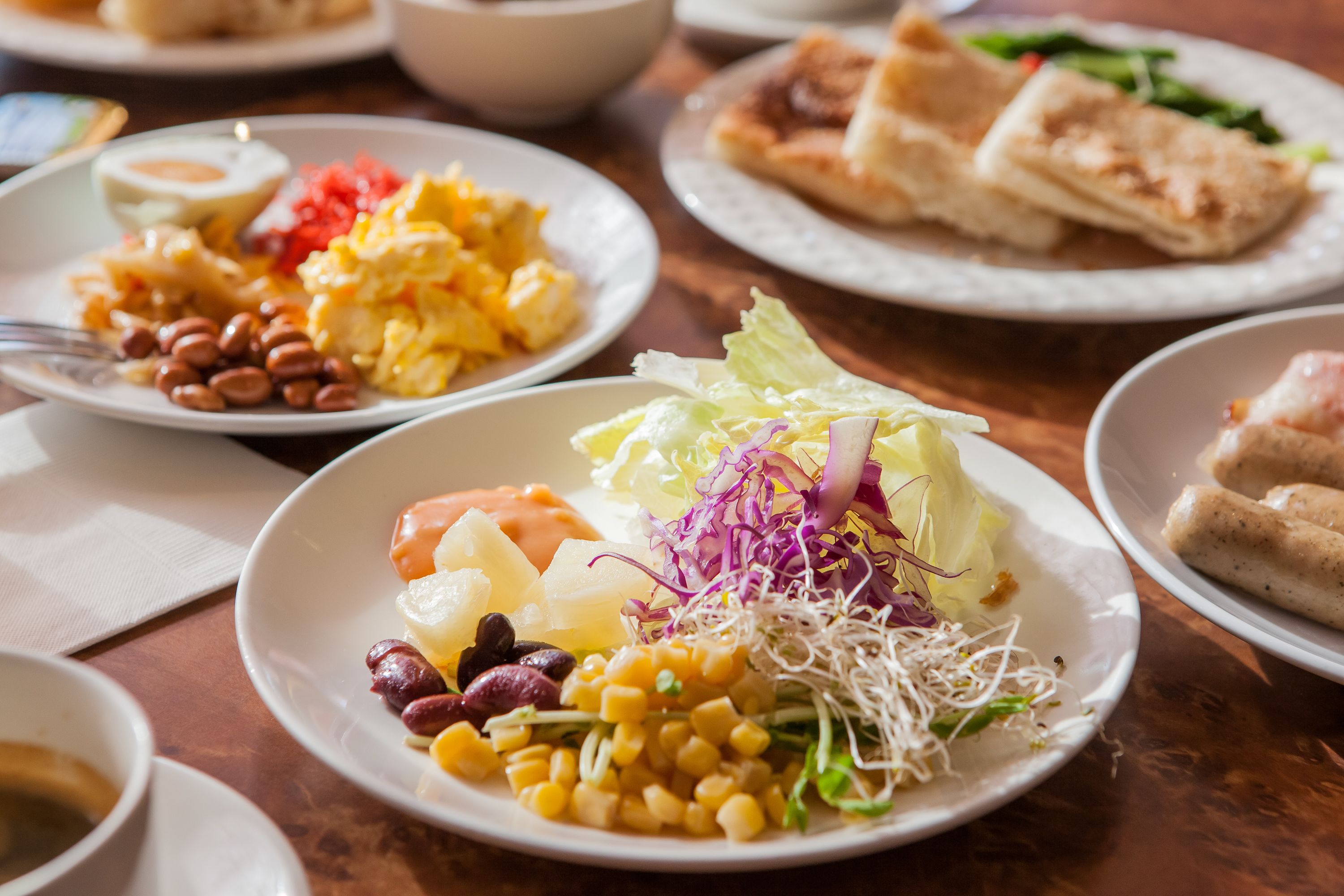 Una variedad de platos sobre una mesa, incluyendo un plato con maíz, frijoles y una ensalada.