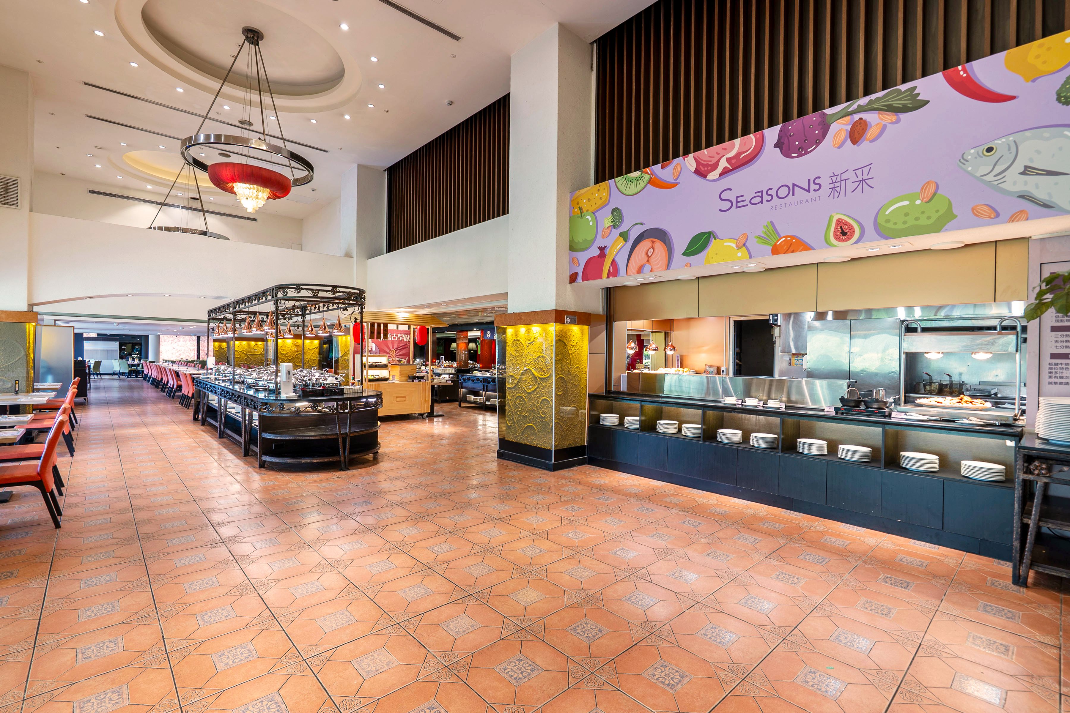 A spacious restaurant with a buffet area, a counter with food displays, and a high ceiling with modern lighting fixtures.