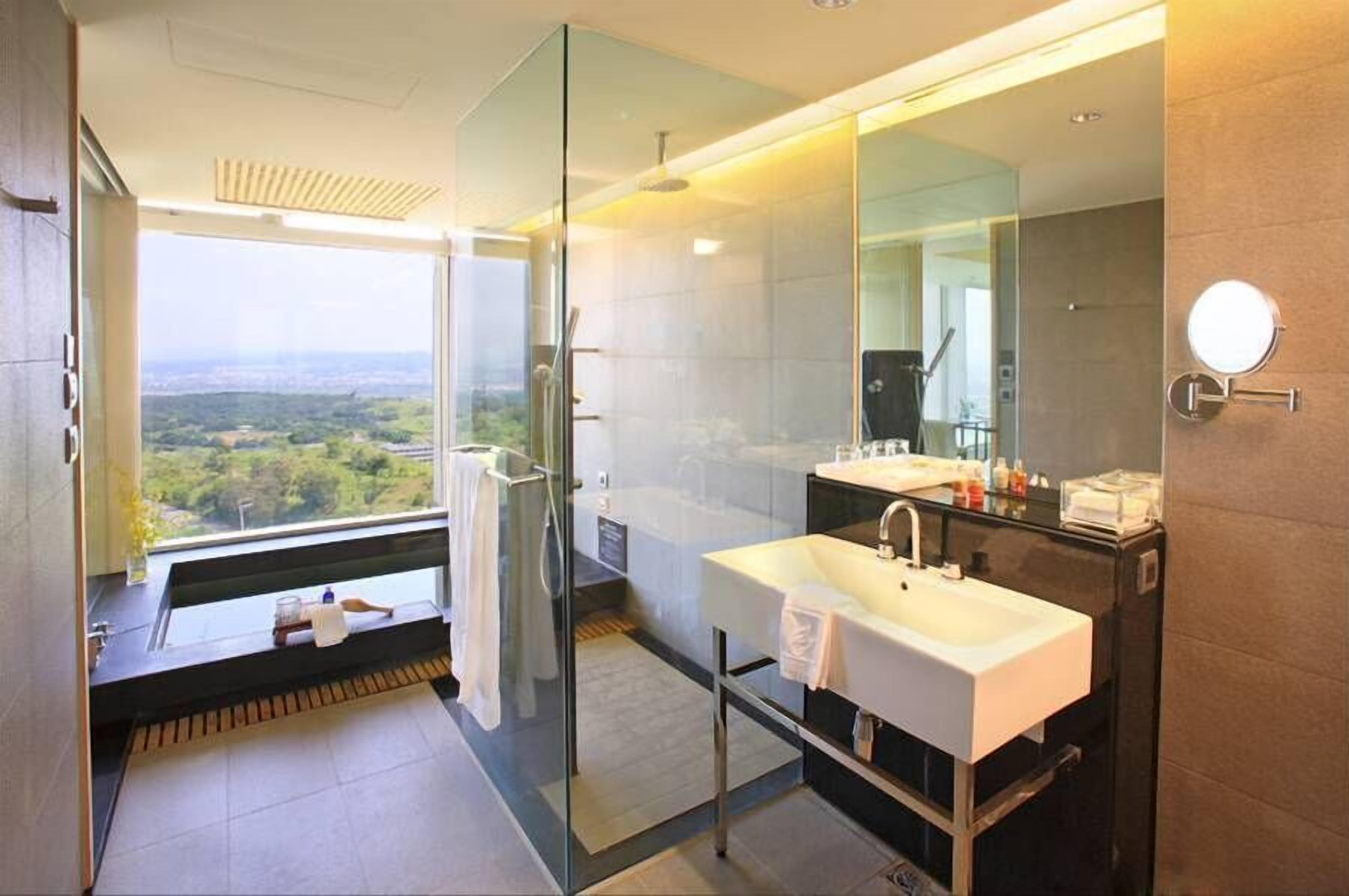 Un baño moderno con un espejo grande, dos lavamanos y una ducha con mampara de vidrio.