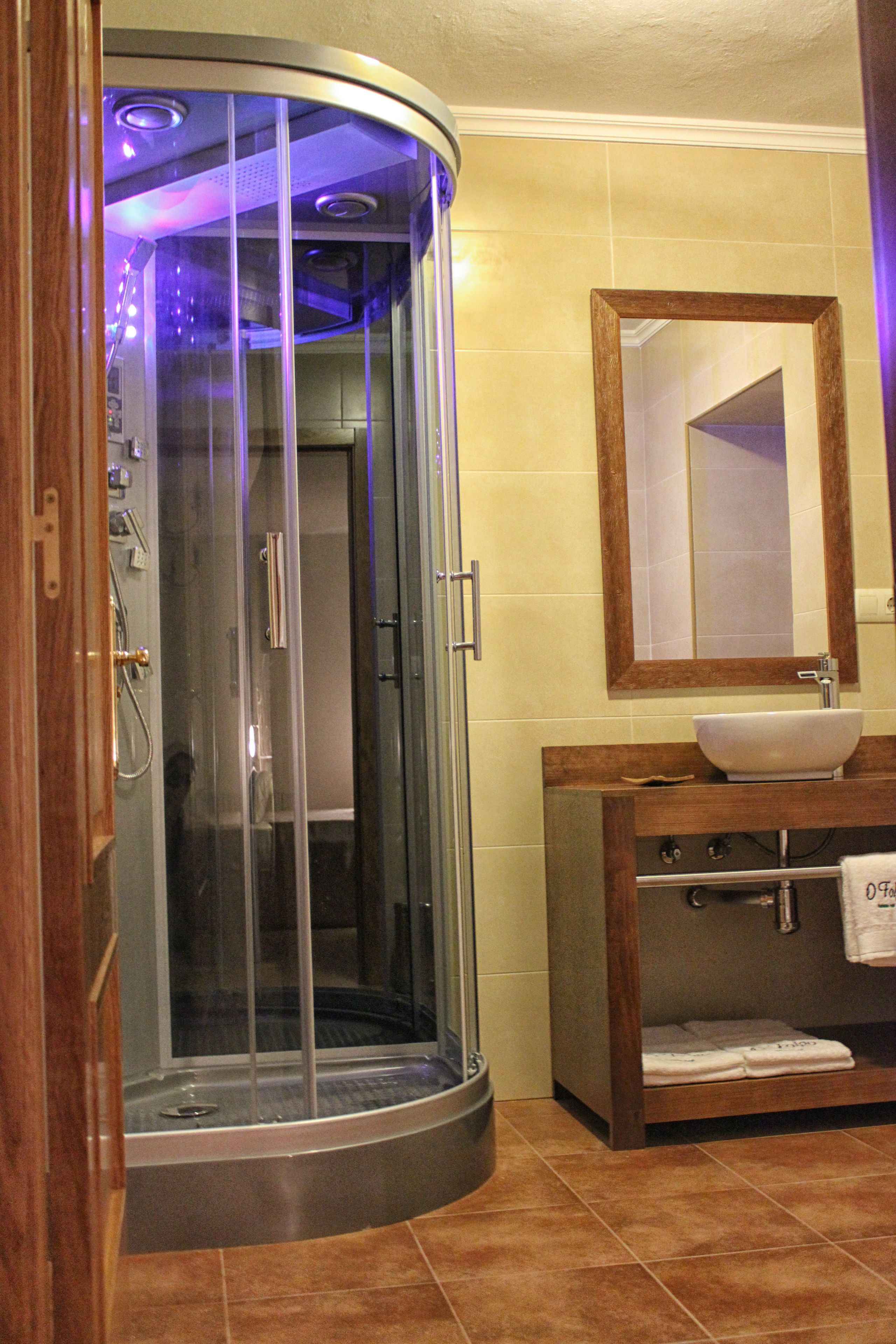 A modern bathroom with a glass-enclosed shower, a wooden vanity with a sink, and a mirror above the vanity.