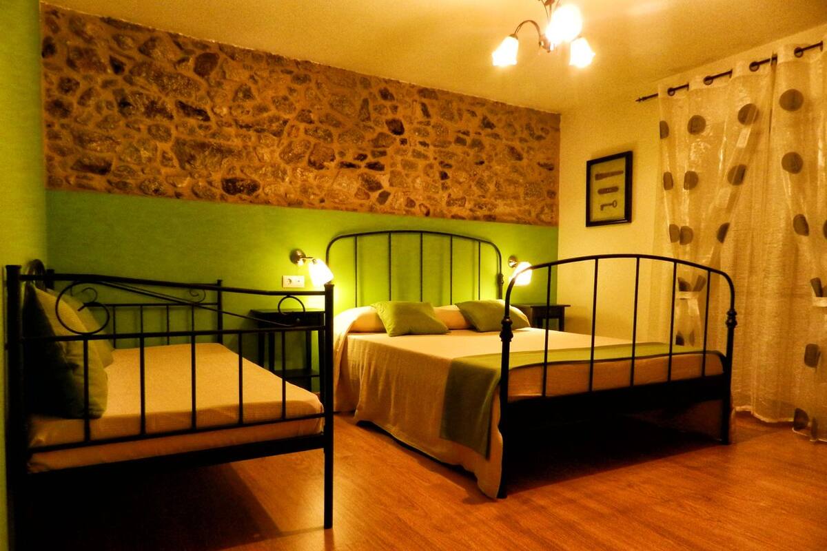 A room with two metal bunk beds, a stone wall, and a wooden floor.