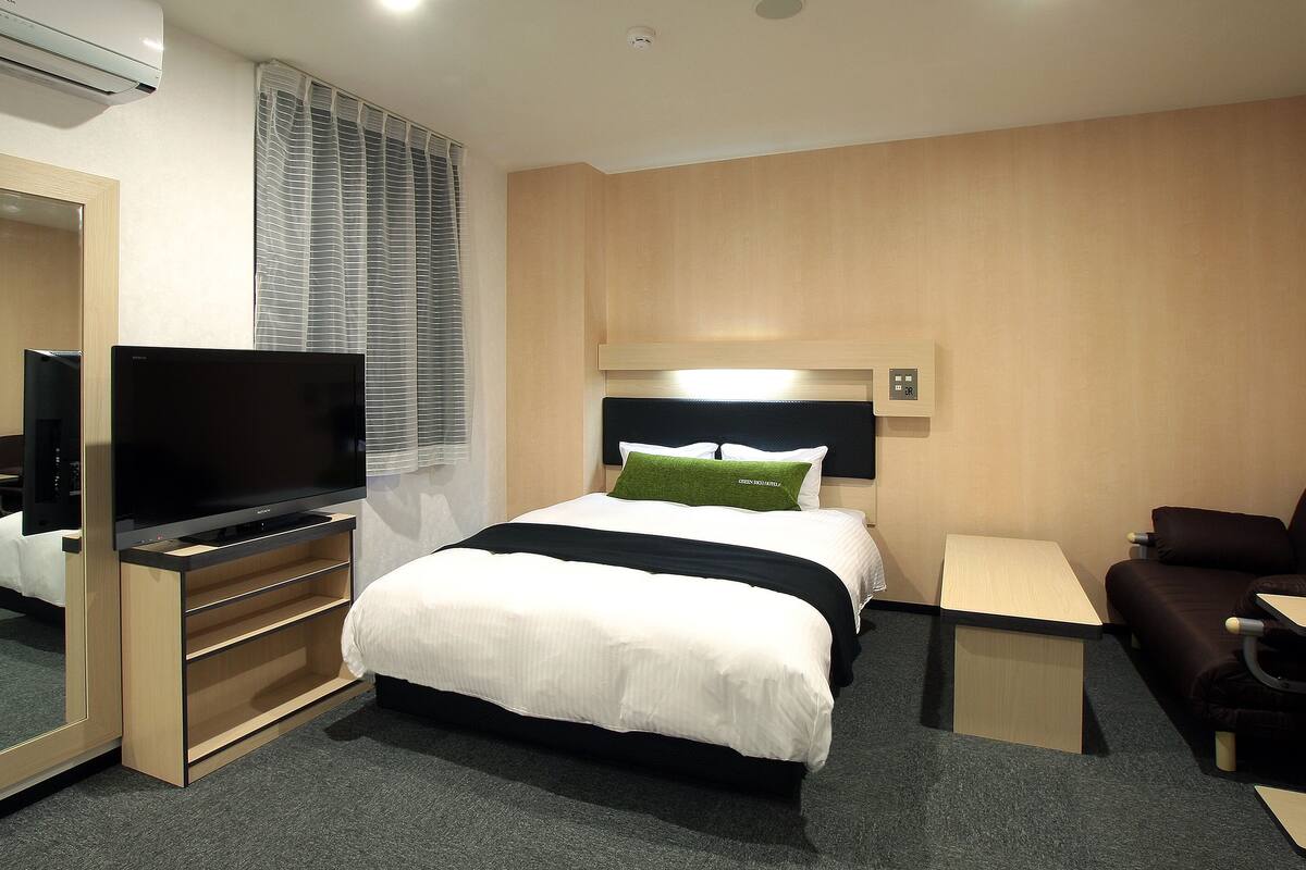 Een hotelkamer met een bed, een televisie, een bureau en een bank.