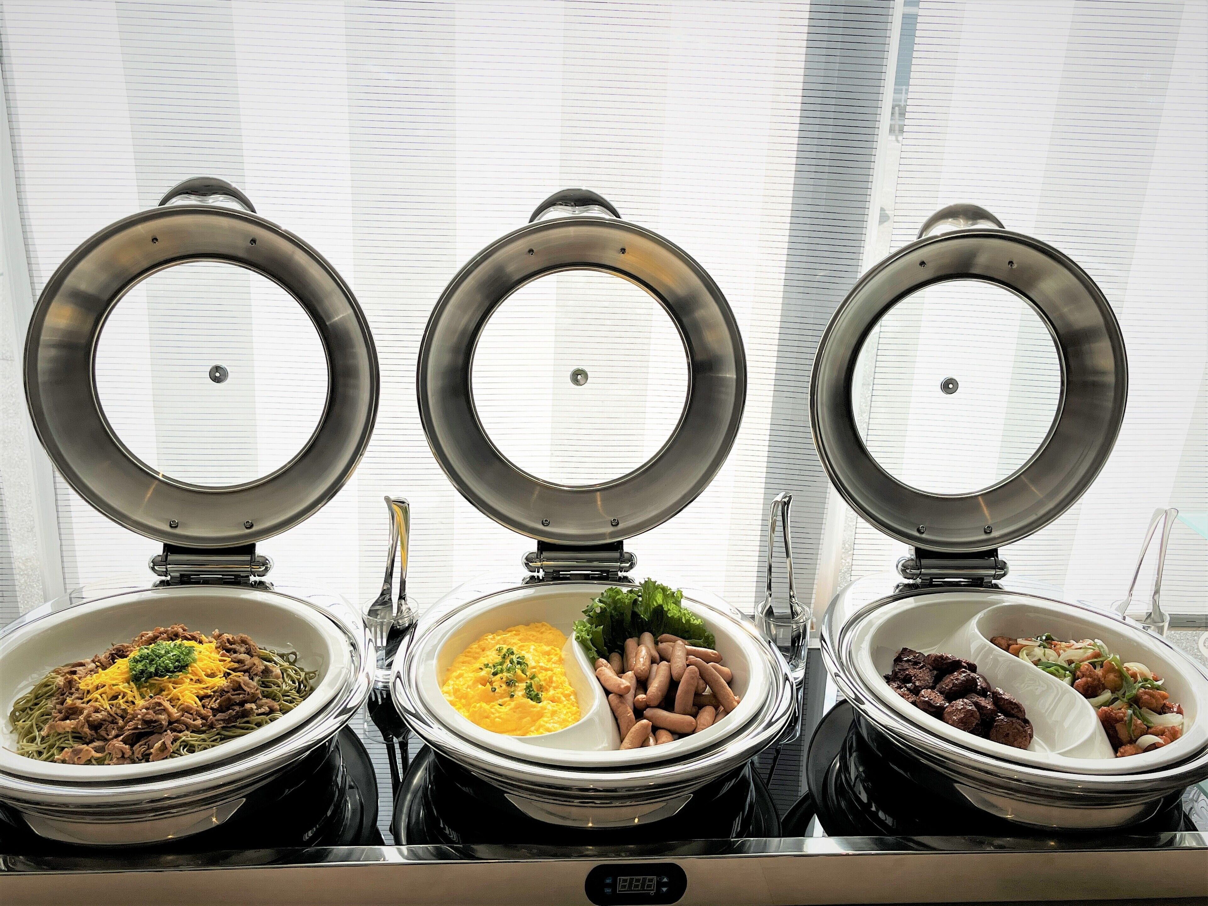 Three buffet bowls with different dishes, each with a lid.