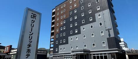 A multi-story hotel with a sign indicating 'Green Rich Hotels' and a parking lot with marked spaces.