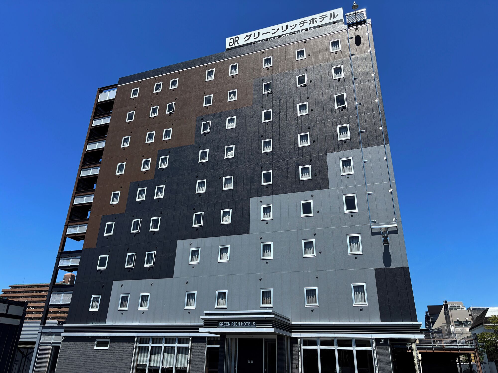 Un edificio de varios pisos con un letrero que indica 'DR. GREEN RICHTEL' y 'GREEN RICH HOTELS' en la parte inferior.