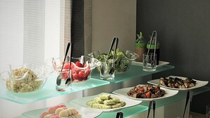 Un buffet proposant une variété de plats, notamment des salades, des fruits et des desserts, présentés sur des étagères en verre.
