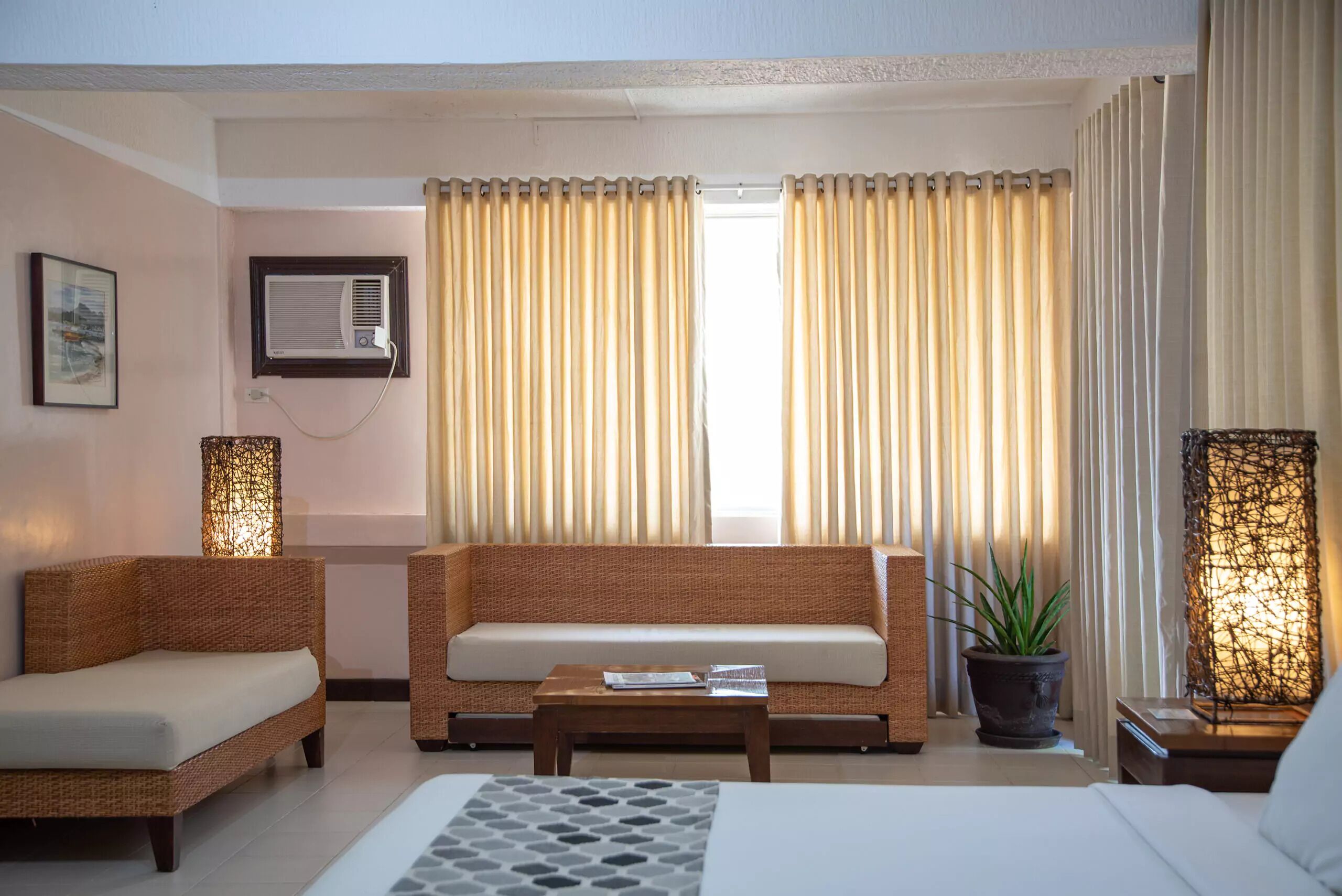 A modern living room with a sofa, two armchairs, a coffee table, and a potted plant.