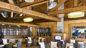 A spacious indoor area with wicker furniture, a television, and a fireplace. - Matabungkay Beach Hotel (Lian)