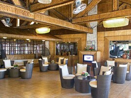 Un amplio espacio interior con muebles de mimbre, televisor y chimenea.
