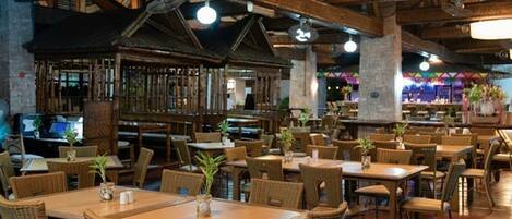 A spacious restaurant with wooden tables and chairs, large hanging lights, and a rustic interior.
