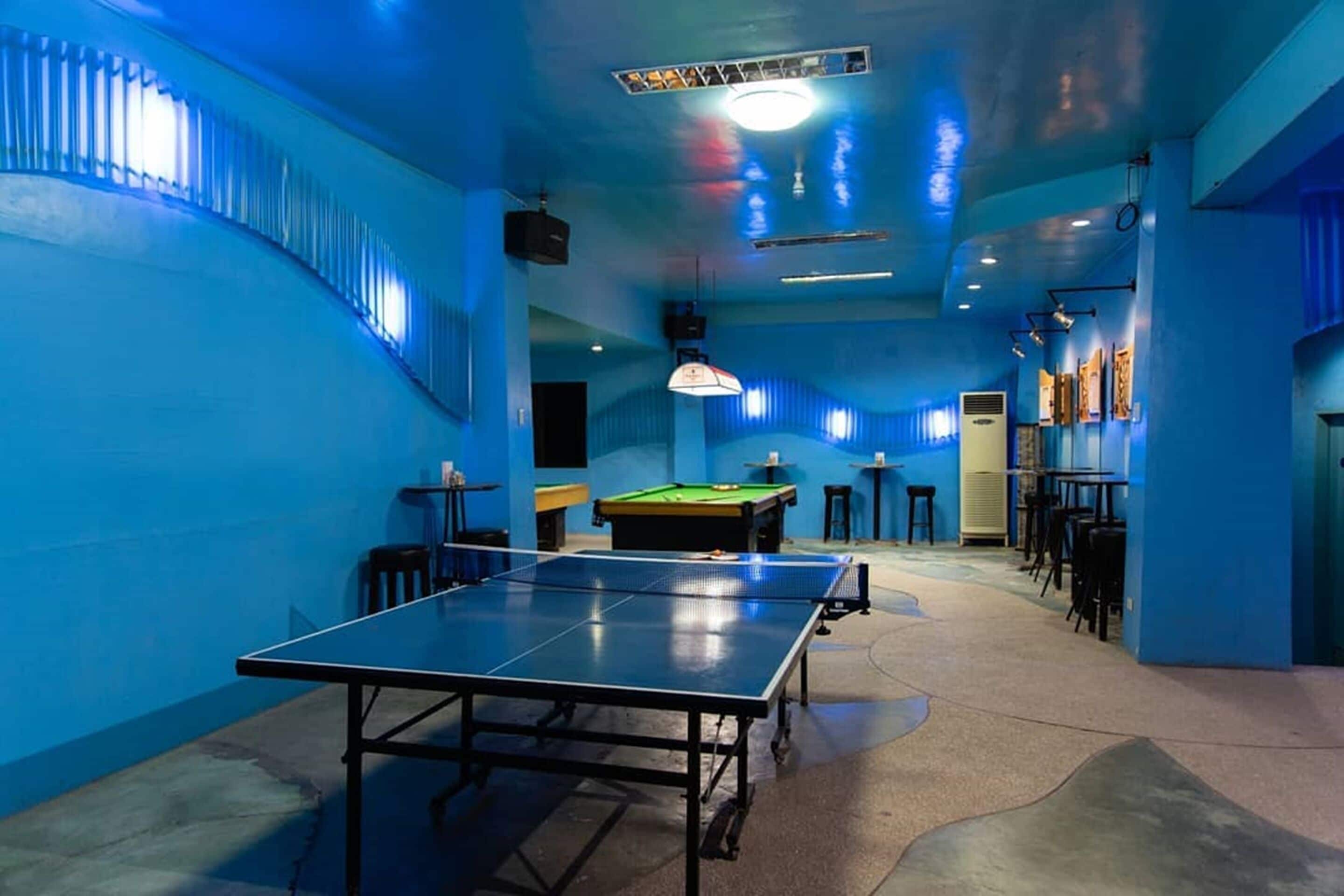 Een kamer met een tafeltennistafel, een pooltafel en een biljarttafel. Er staan stoelen en tafels rondom de tafels gezet.