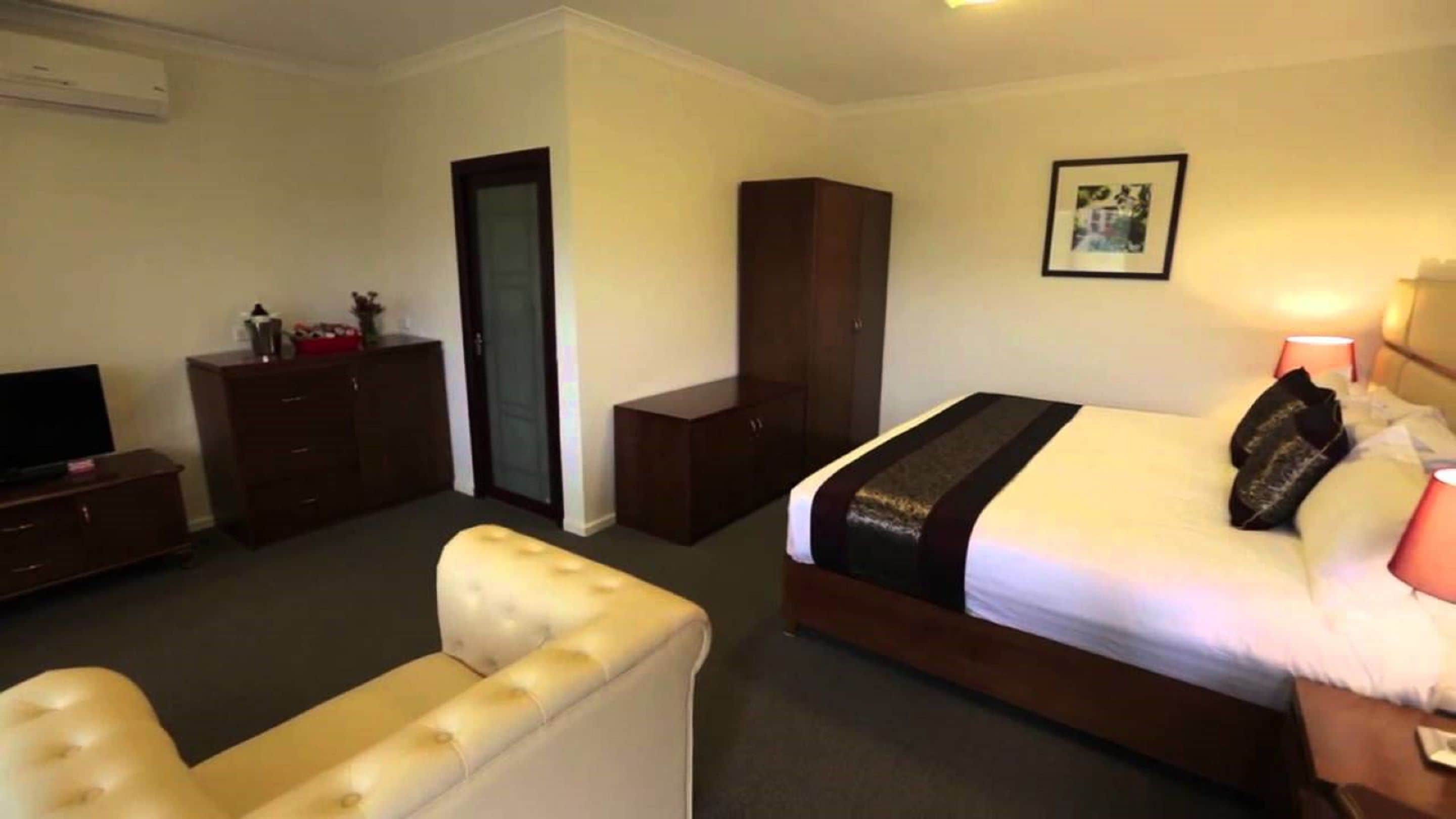 Une chambre d’hôtel comprenant un lit, une télévision, une armoire, une petite table et un canapé.