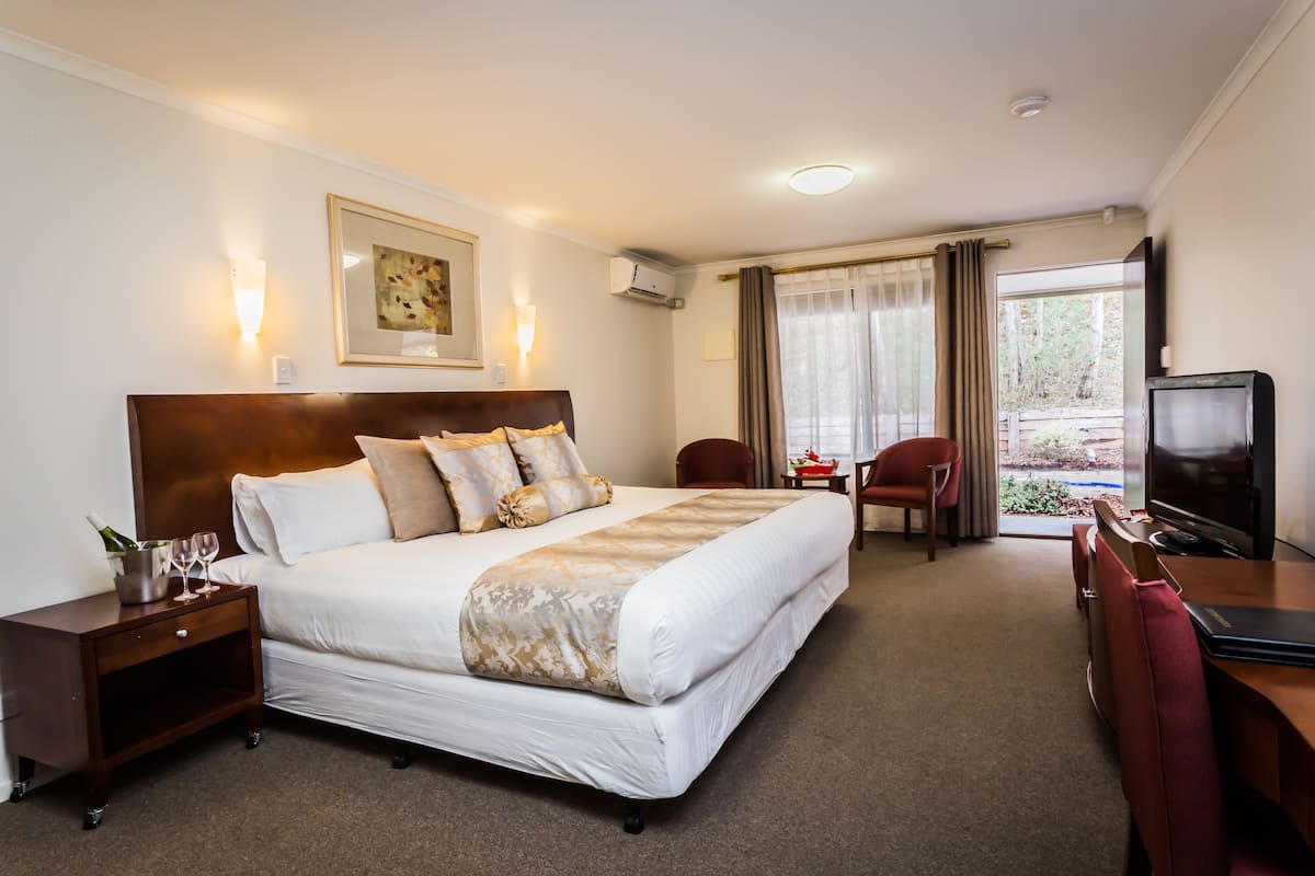 Una habitación de hotel con una cama grande, un escritorio con una silla, un televisor y una ventana con cortinas.