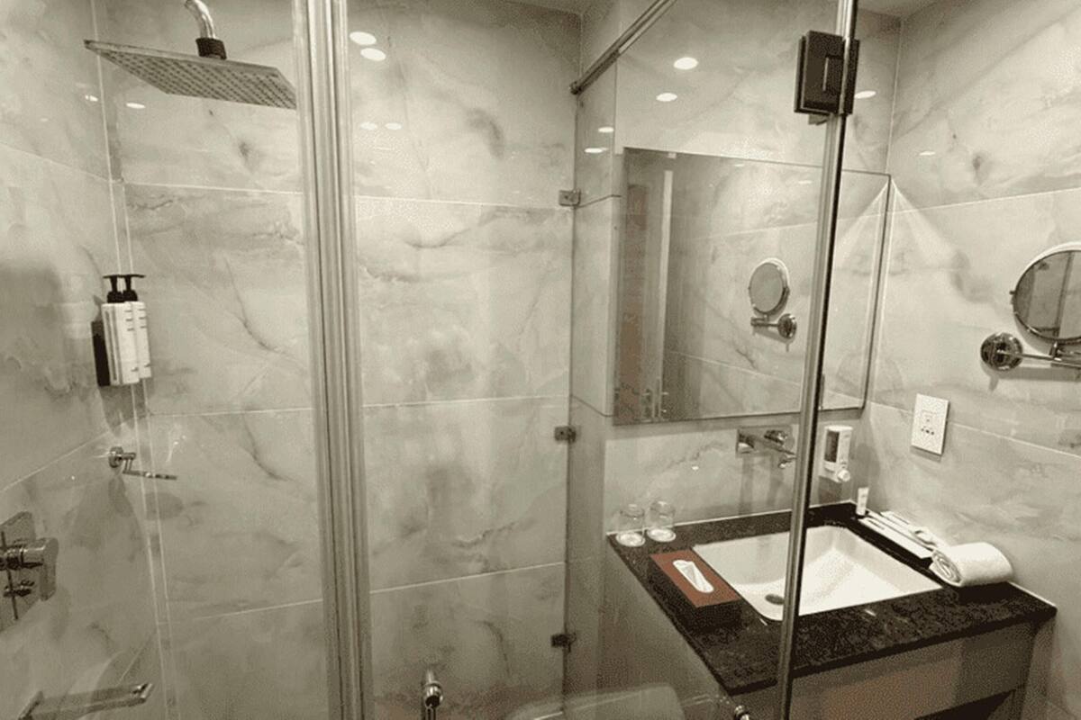 A modern bathroom with a glass-enclosed shower, a marble vanity, and a large mirror.