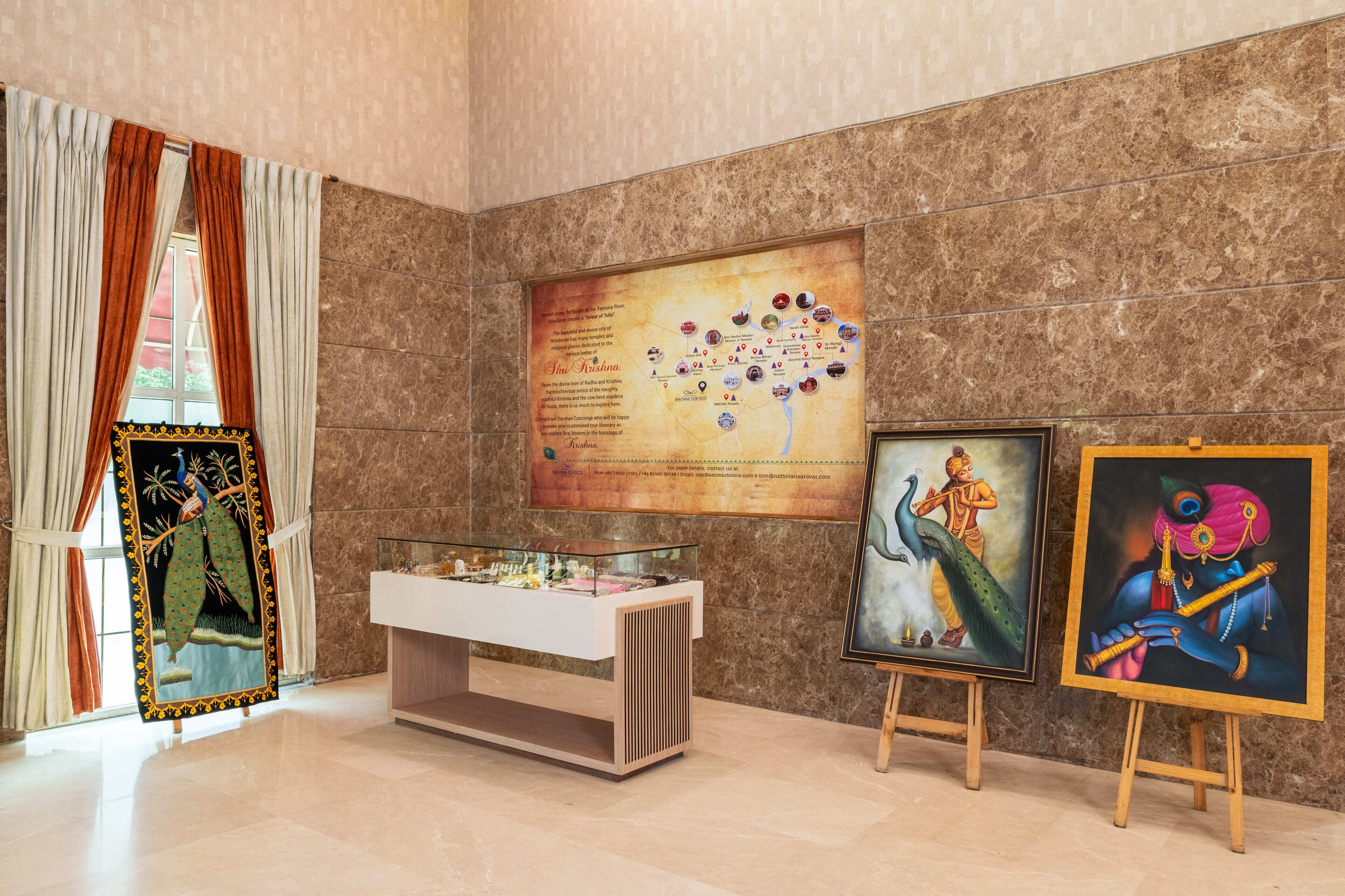 A room with a marble wall, a glass display case, and two paintings.