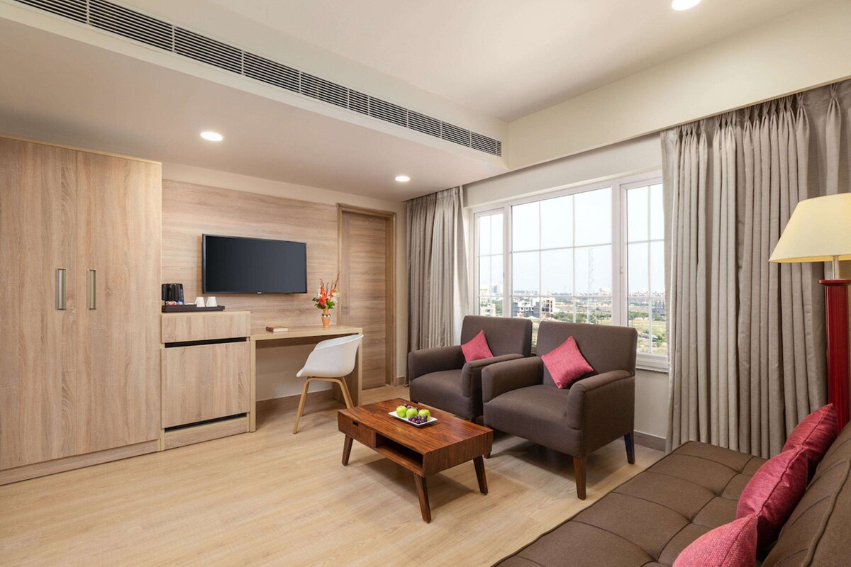 A modern living room with a sofa, armchair, coffee table, TV, and a desk with a chair.
