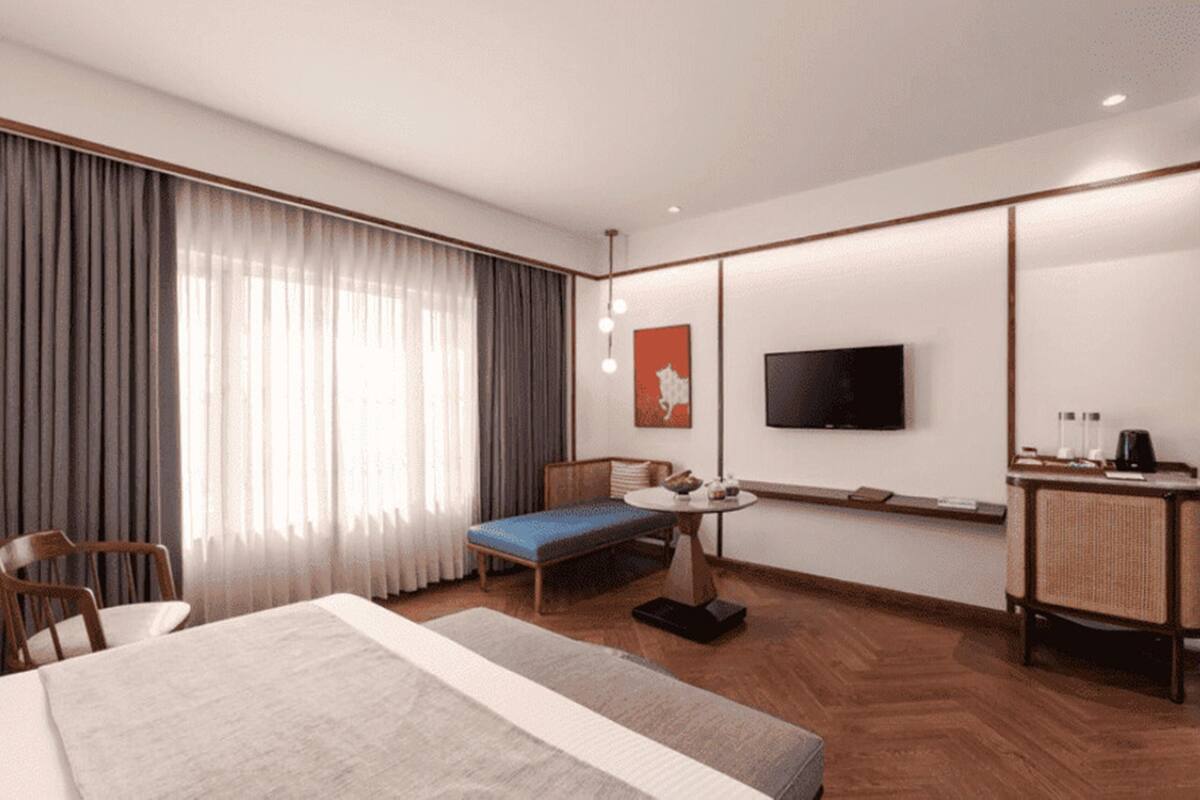 A hotel room with a bed, a desk, a chair, a television, and a window with curtains.