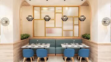 A restaurant with a green booth seating area, blue chairs, and a geometric patterned wall.