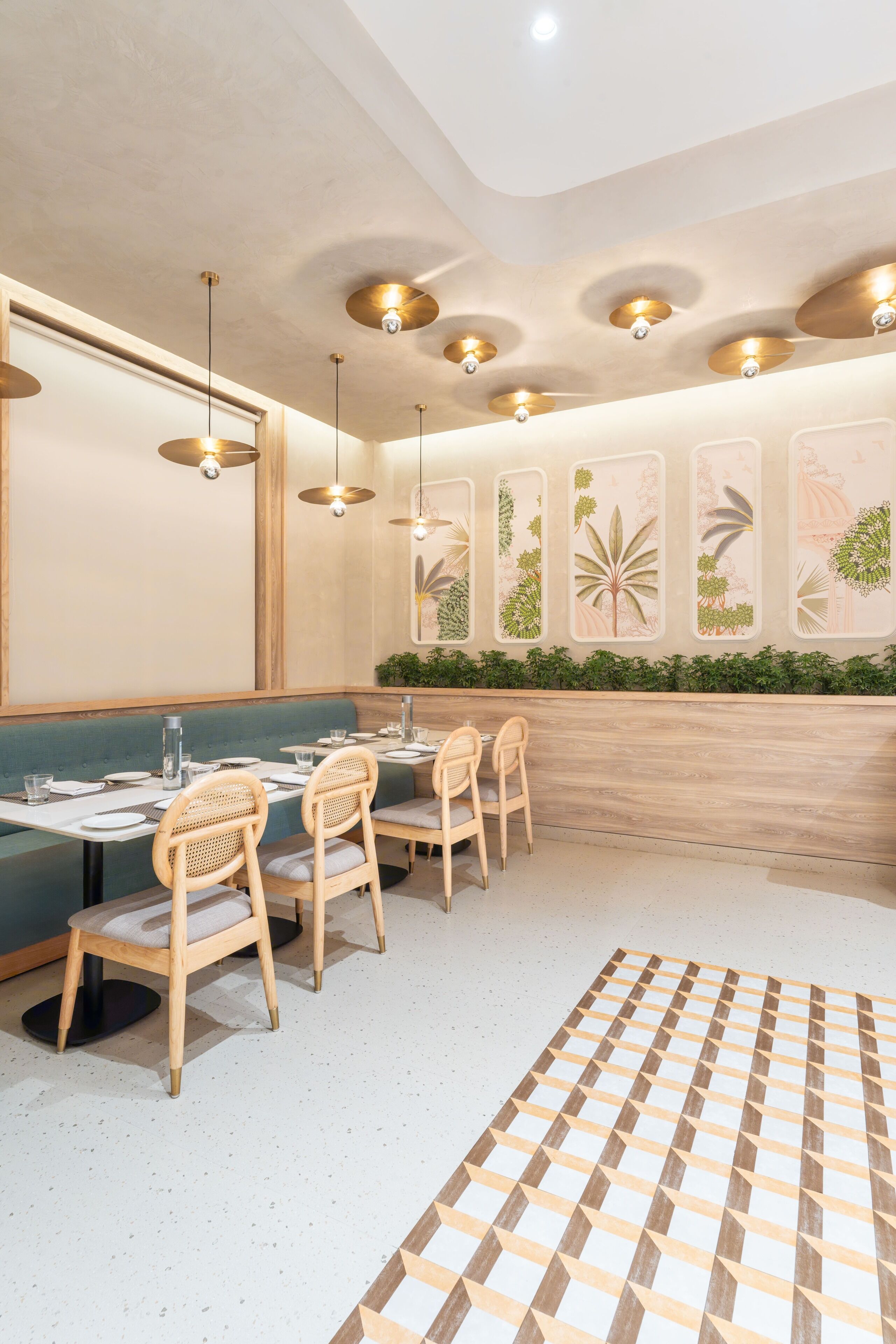 A restaurant with a green booth seating area, wooden chairs, and a patterned rug.