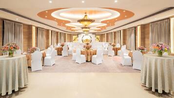 A spacious banquet hall with round tables, white chairs, and floral centerpieces.